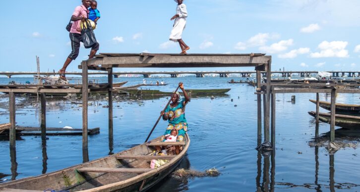 Full shot of a group of african people passing over and under a makeshift bridge.