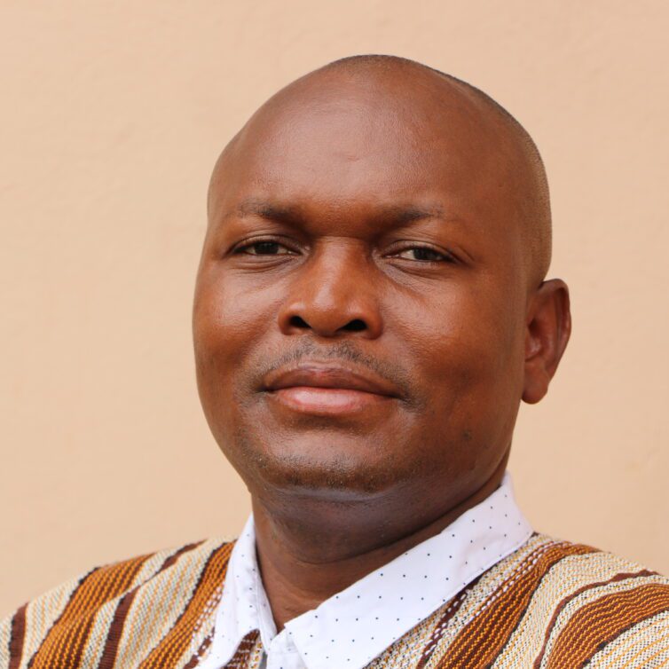 Headshot of Kusimi John Manyimadin, a bold man smiling at the camera.