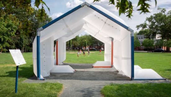 A white pavillion generating shade in a small playground where children are running