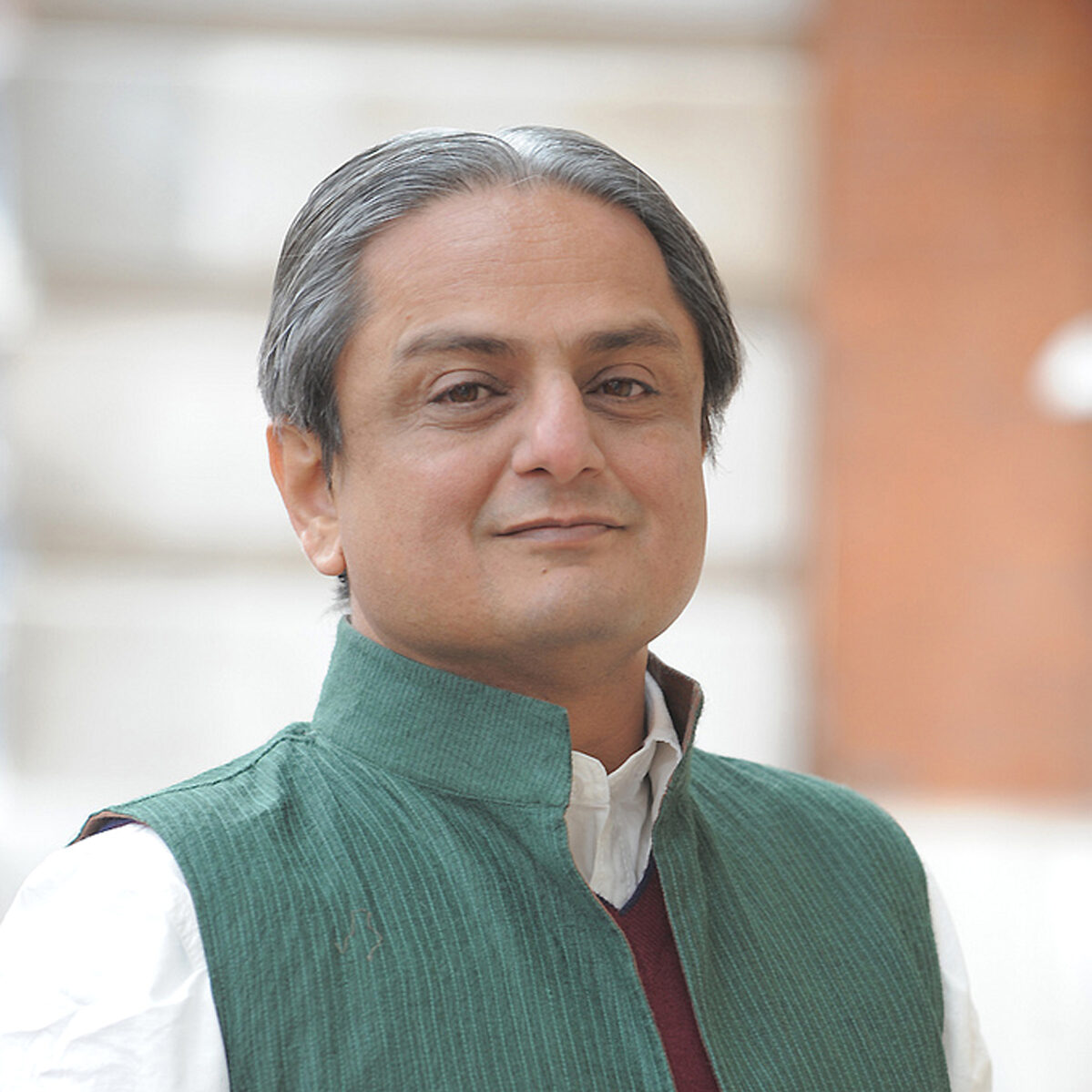 Headshot of Mihir Bhatt, headshot of a man with salt and pepper hair wearing a green top.