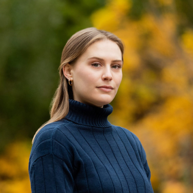 Portrait of Oona Gaffney, blond hair woman wearing a blue turtle neck.