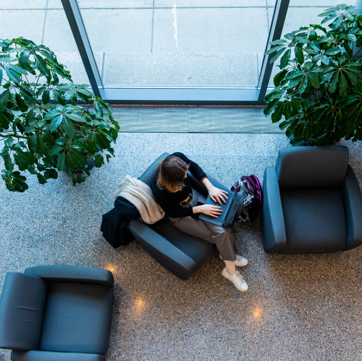 Aerial view of a young woman with a laptop sitting in a lounge.