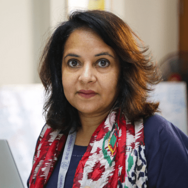 Headshot of Sabina Faiz Rashid, headshot of a brown hair and brown eyes woman wearing a colorful scarf.