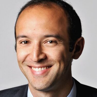 Headshot of Solomon Hsiang, headshot of a man with short black hair and brown eyes smiling at the camera.