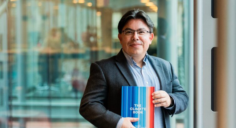 Profile shot of Mauricio Santillana holding his new book