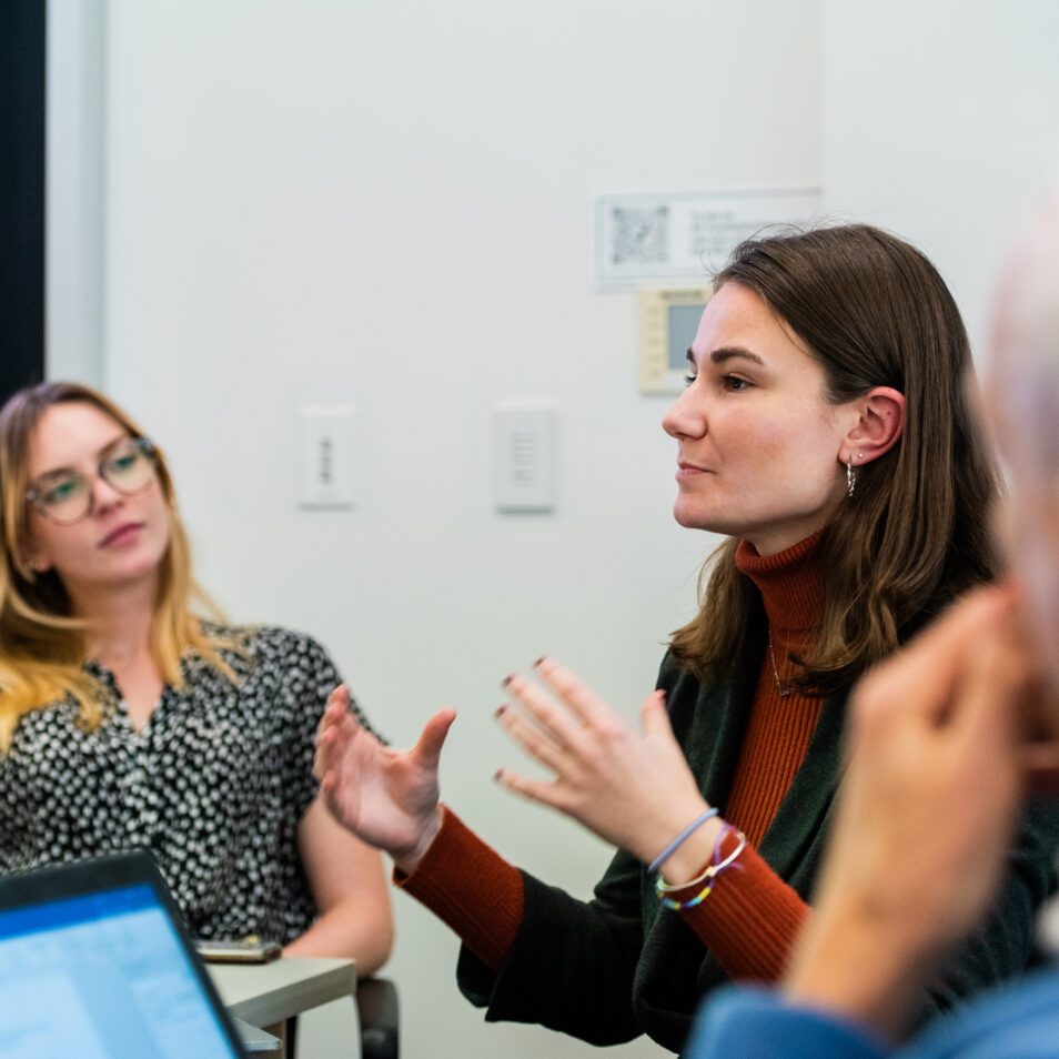 Caucasian woman talking to a group of people.
