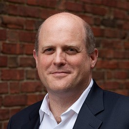 Headshot of Dan Schrag, headshot of a man with grey hai, wearing a suit and smiling at the camera.