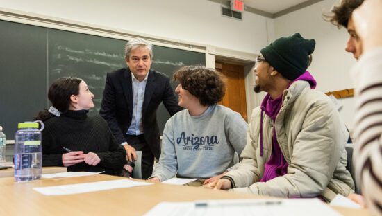 Students sitting at a table in a classroom interact with Professor Stephen Ansolabehere.