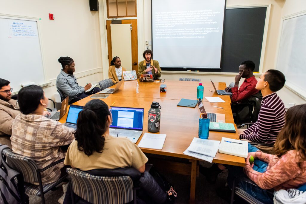 An image of the classroom where students in Professor Daniel Agbibo's class, Mobility, Power, and Politics sit in a round-table discussion.