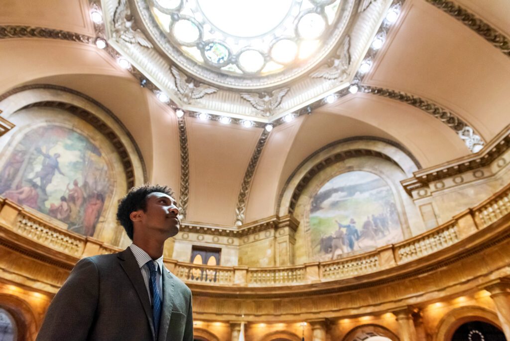 Chris Mesfin looks up towards the dome of the Massachusetts State Capitol.