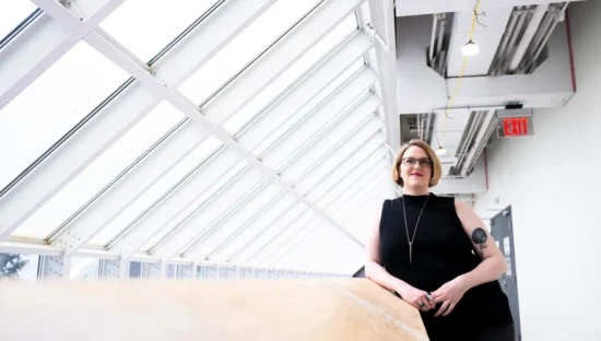 Dr. Colleen Lanier-Christensen leans on a railing under skylights.