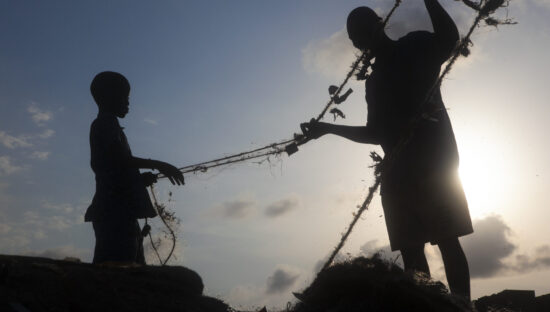 A father and son sort a fishing net in Nigeria (David Trilling)