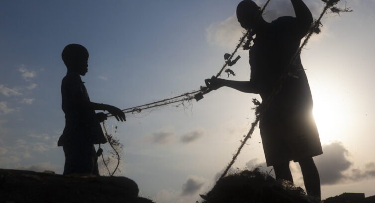 A father and son sort a fishing net in Nigeria (David Trilling)